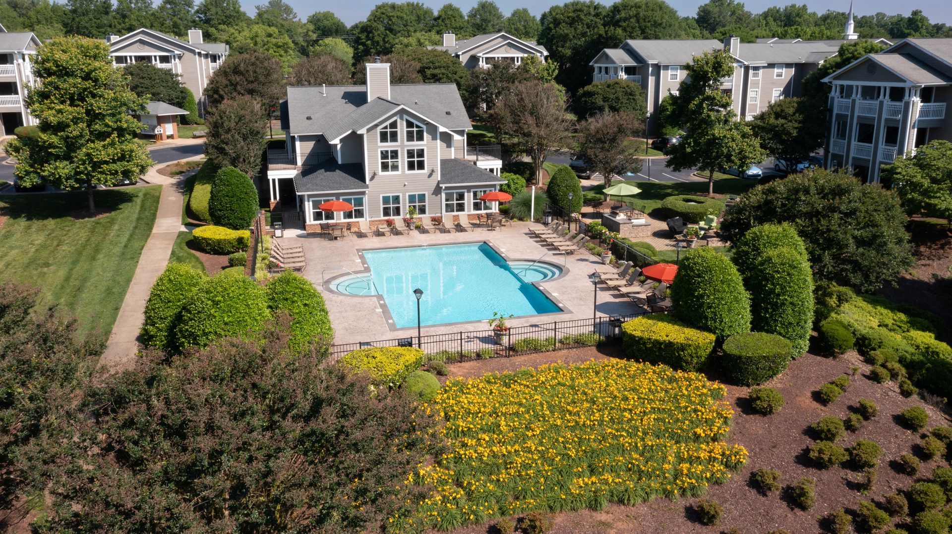 Swimming pool surrounded by landscaping and residential buildings.