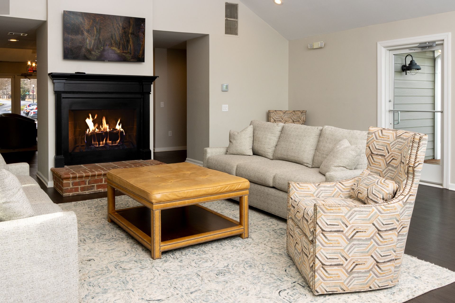 Cozy living room with fireplace, sofas, and a patterned armchair. Fire burning in the hearth.
