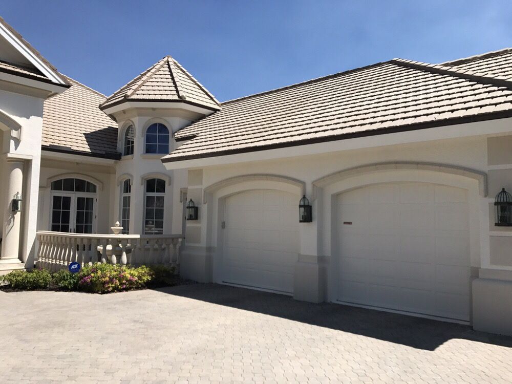 A large white house with a brick driveway in front of it