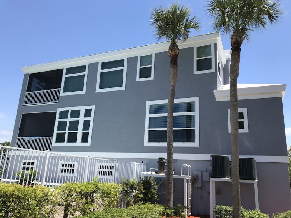 A large gray house with palm trees in front of it