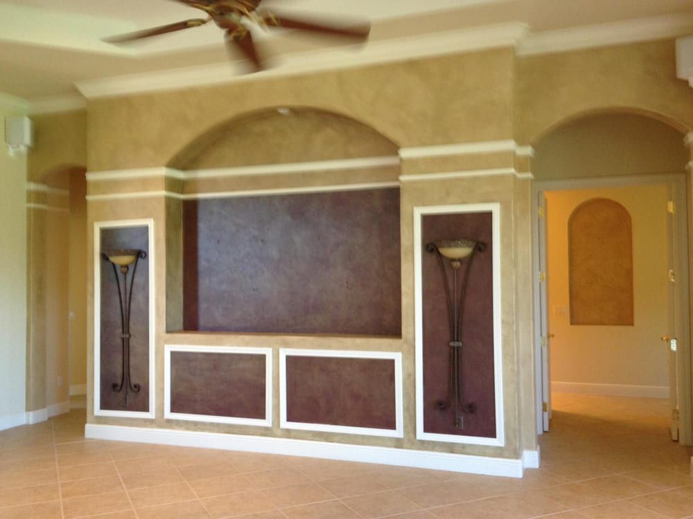 An empty living room with a ceiling fan and a wall mounted entertainment center