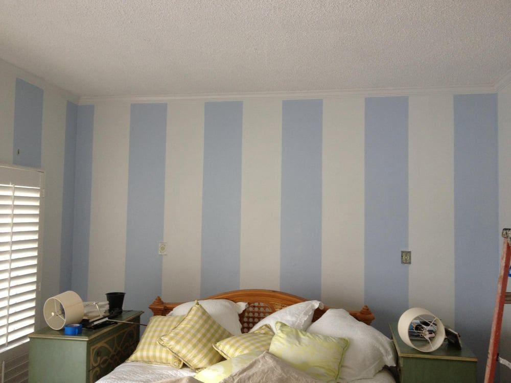 A bedroom with blue and white stripes on the walls