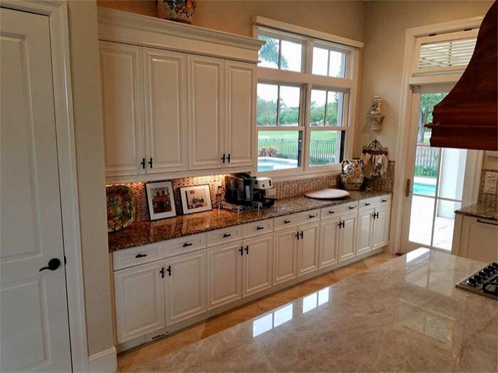 A kitchen with white cabinets and granite counter tops.