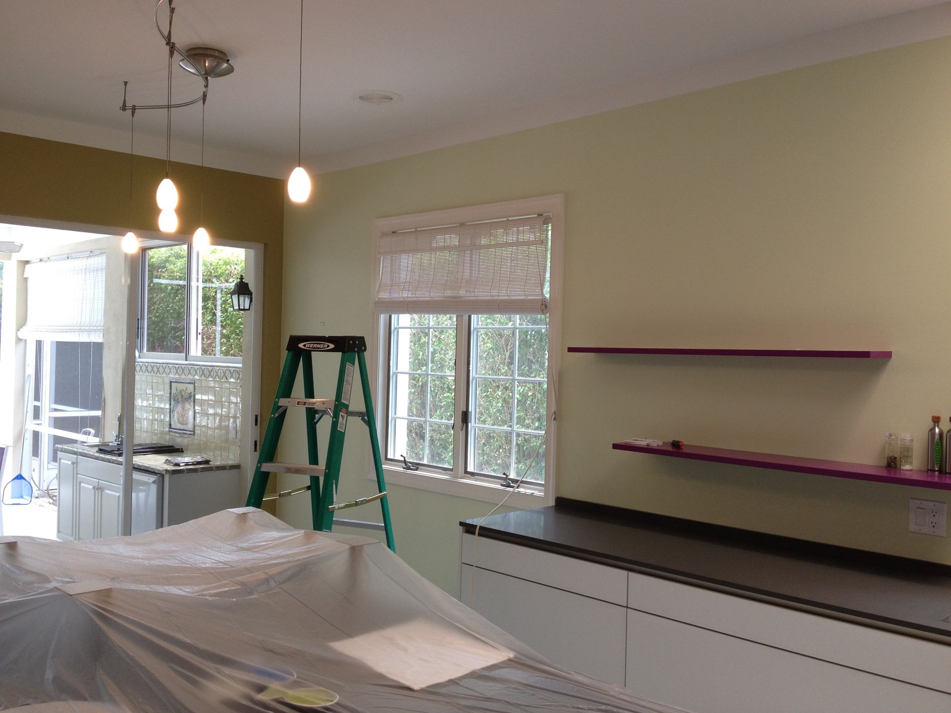 A kitchen with a green ladder and purple shelves