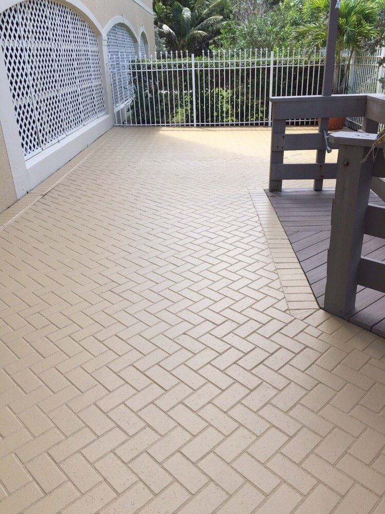 A patio with a herringbone pattern and a wooden deck.