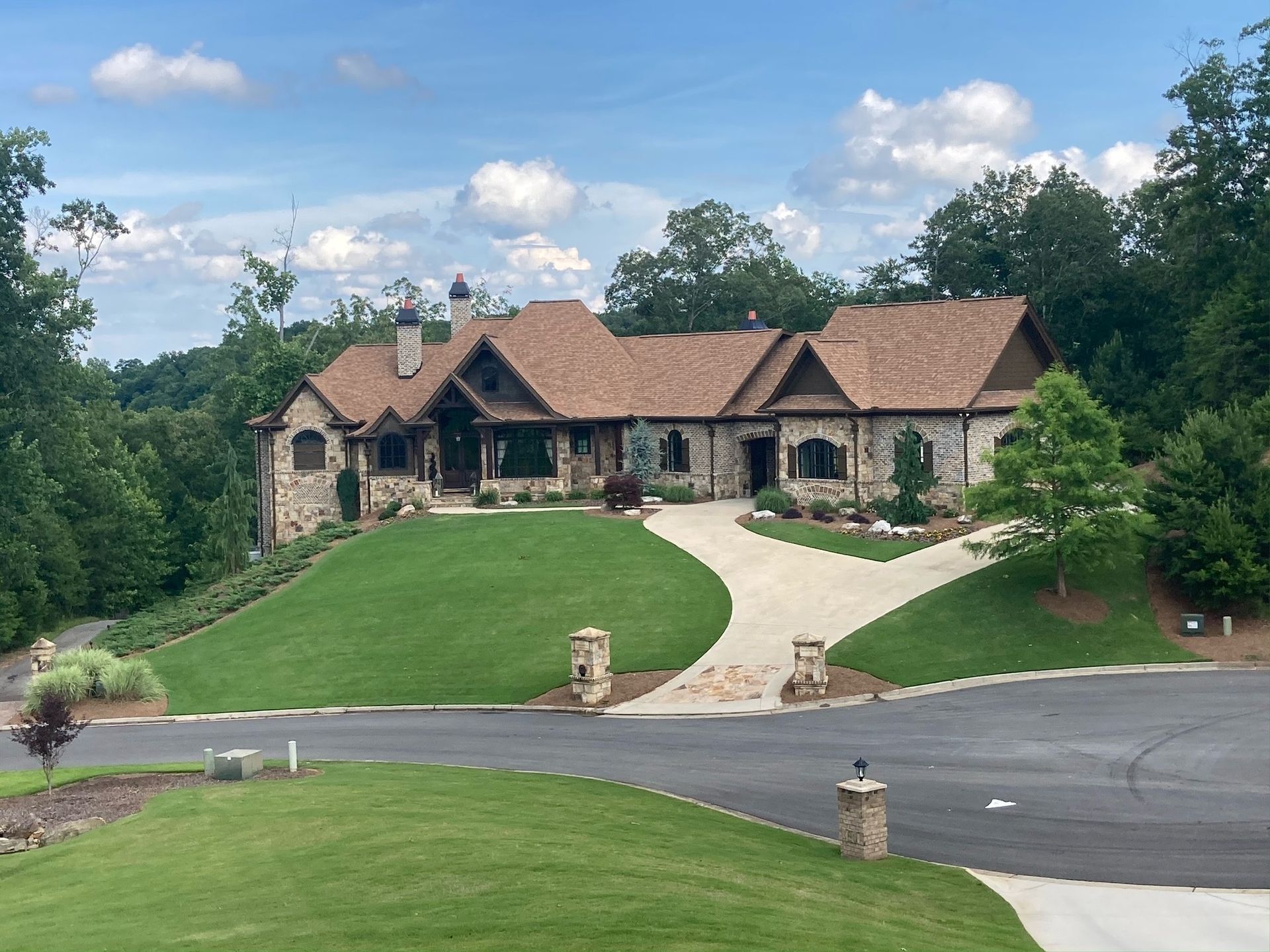 A large house sits on top of a lush green hillside