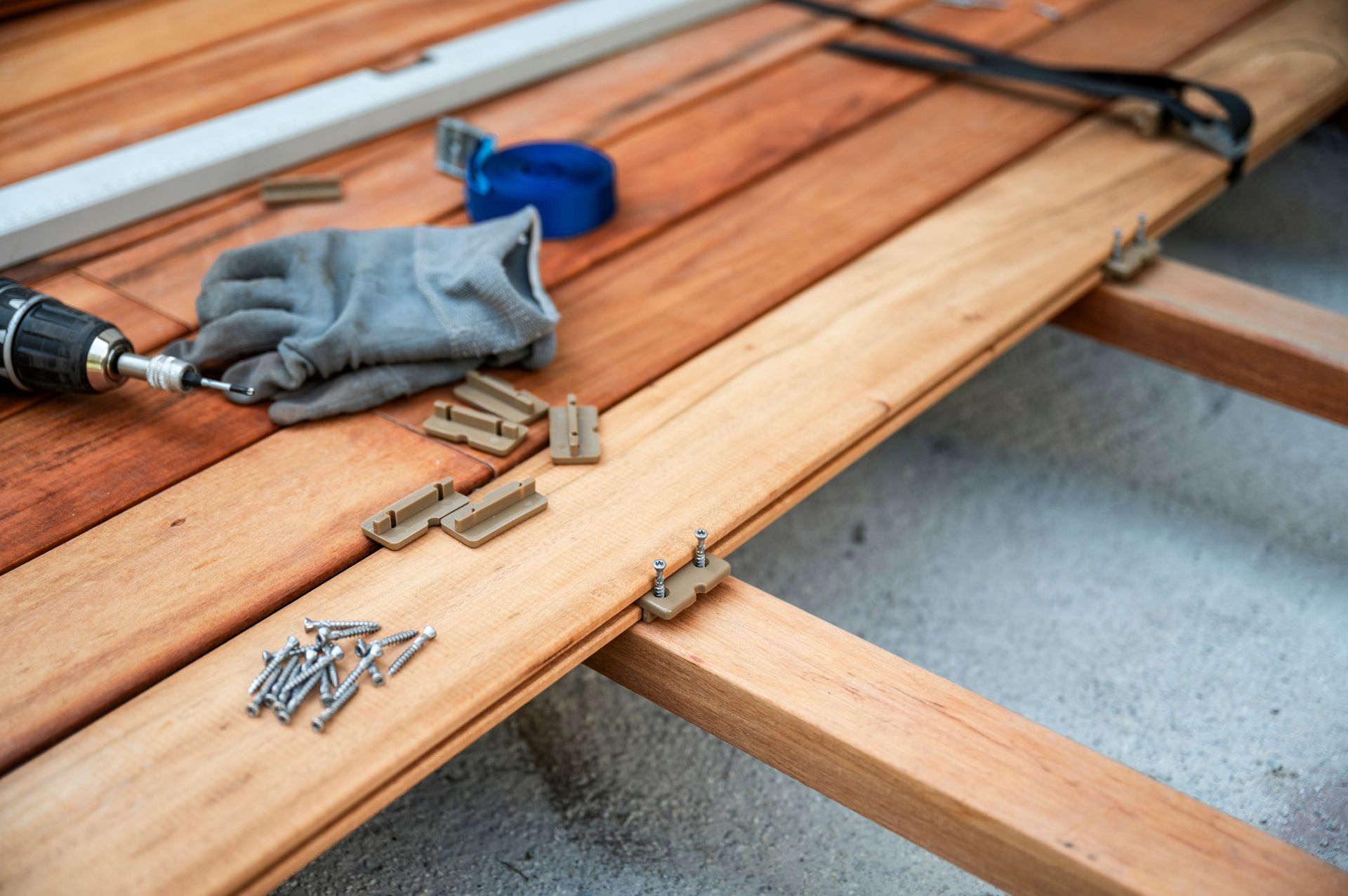 Wooden deck being constructed; tools and fasteners visible.
