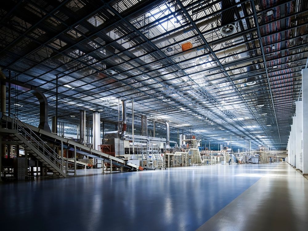 A large empty factory with lots of machinery and stairs.