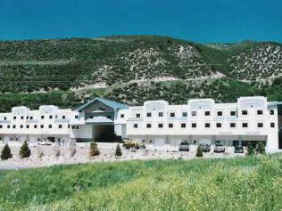A large white building is sitting in the middle of a grassy field.