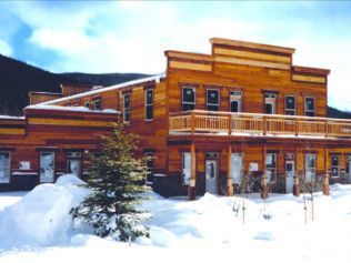 A large wooden building in the snow with mountains in the background