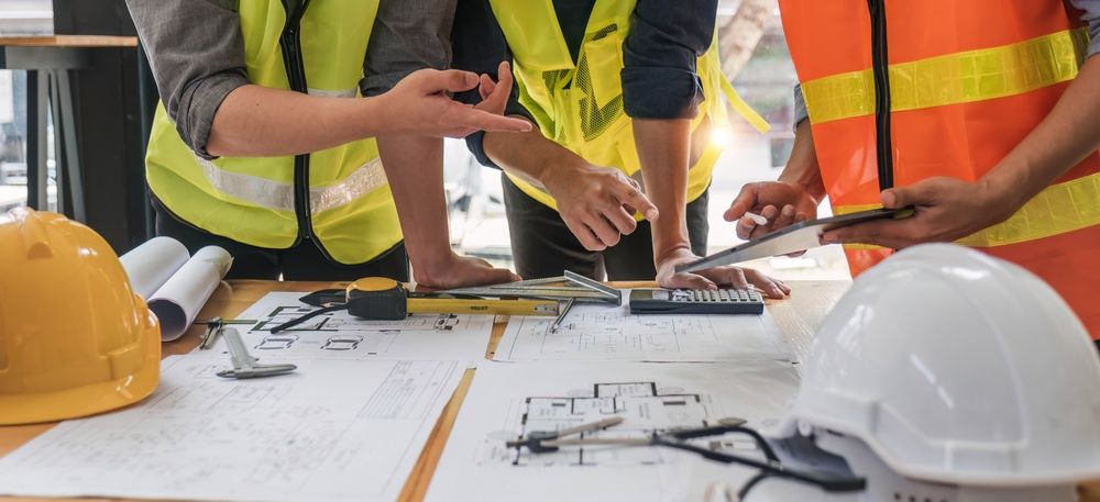 A group of construction workers are standing around a table looking at a blueprint.