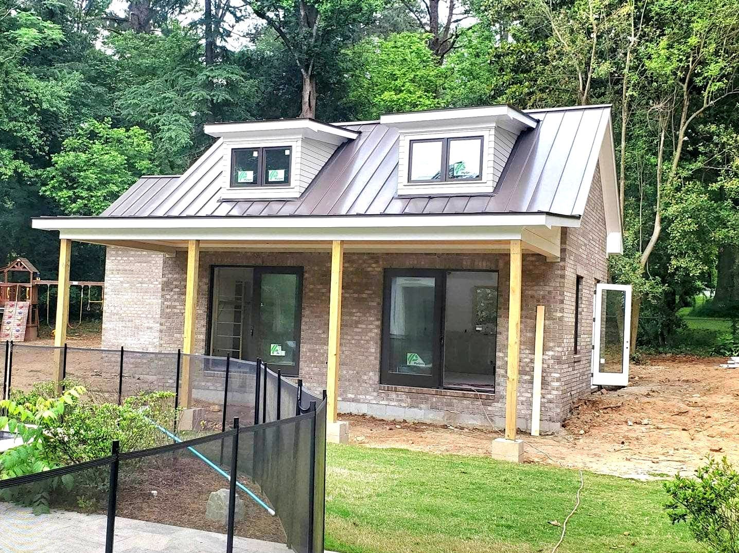 A small house with a metal roof is being built in the woods.