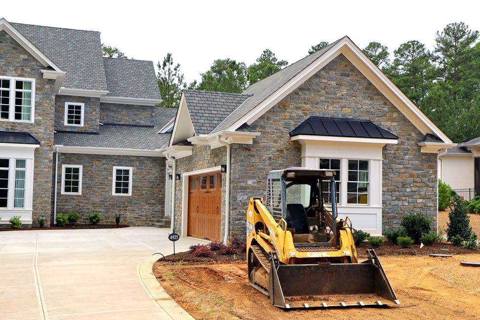 A bulldozer is parked in front of a large house
