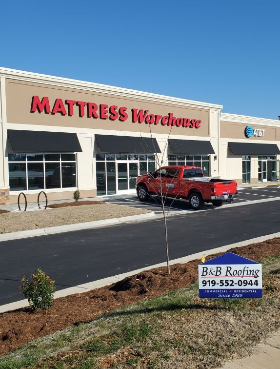 Mattress Warehouse storefront, red pickup truck, B&B Roofing sign in Apex, NC.