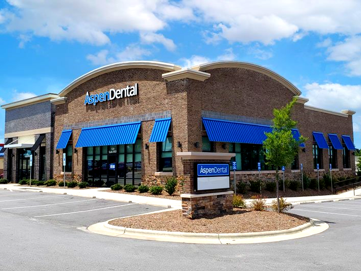 A dental office with blue awnings and a sign in front of it.