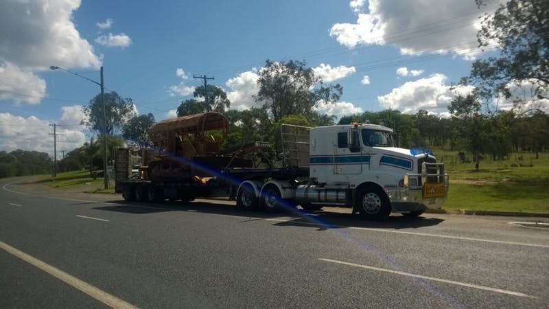 A white truck is driving down a road with a trailer attached to it.
