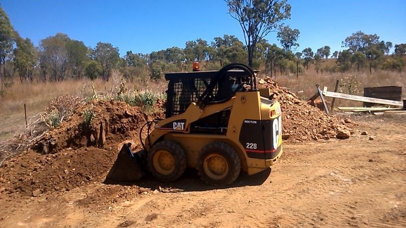 A cat bulldozer is moving dirt in a field
