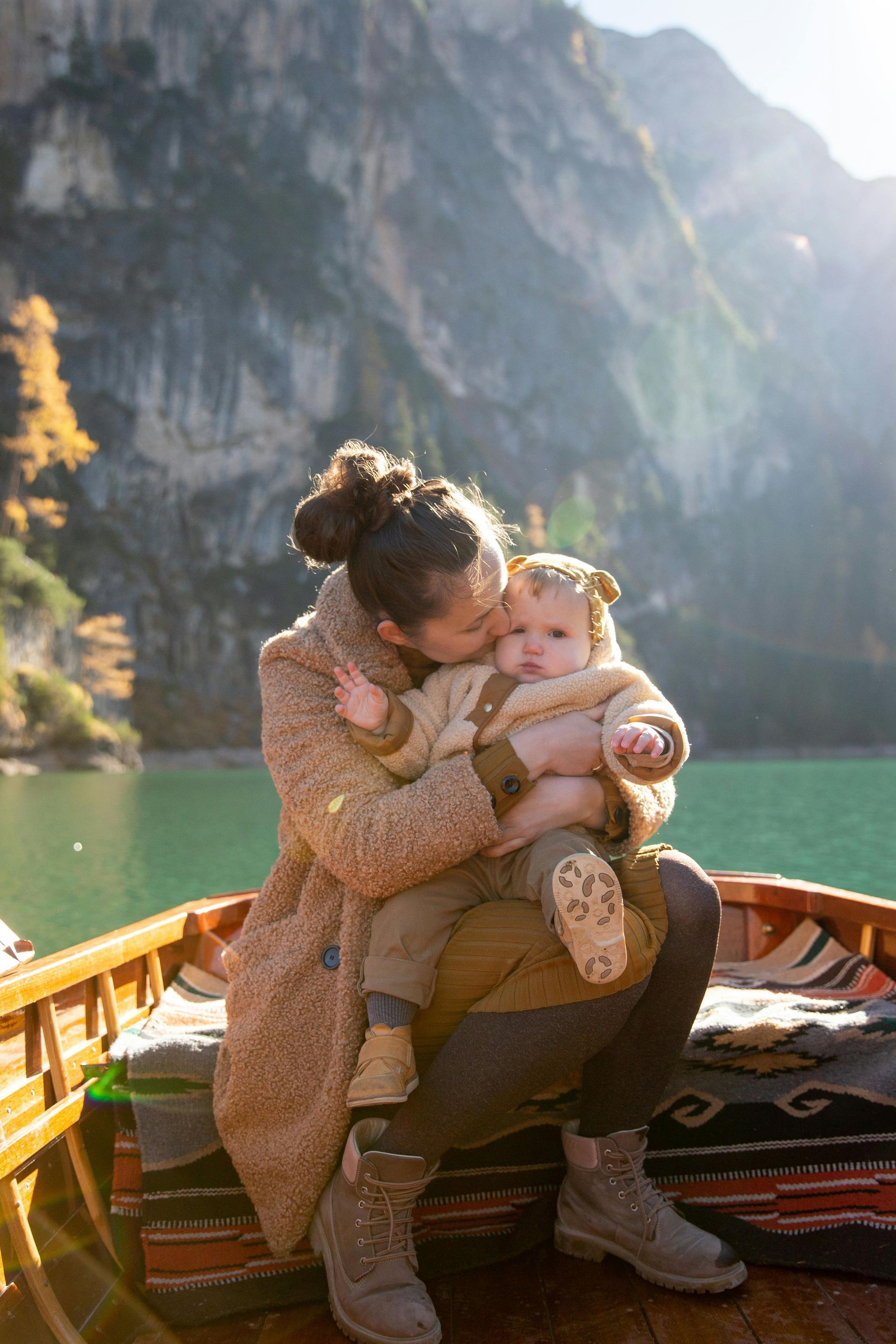 A woman is sitting in a boat holding a baby.