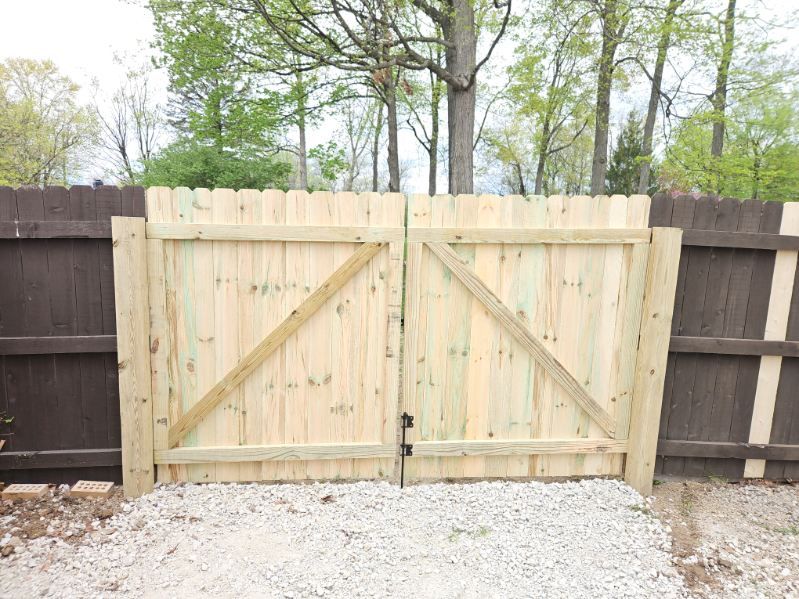 A wooden gate is sitting next to a wooden fence.