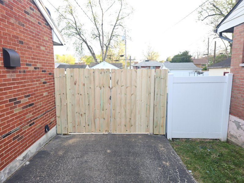 A wooden gate is sitting next to a wooden fence.