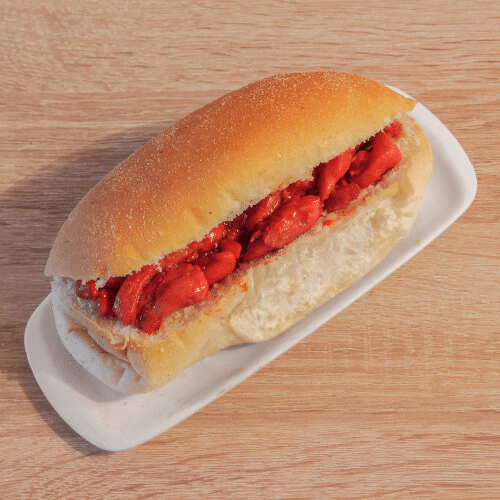 Een hotdog staat op een wit bord op een houten tafel