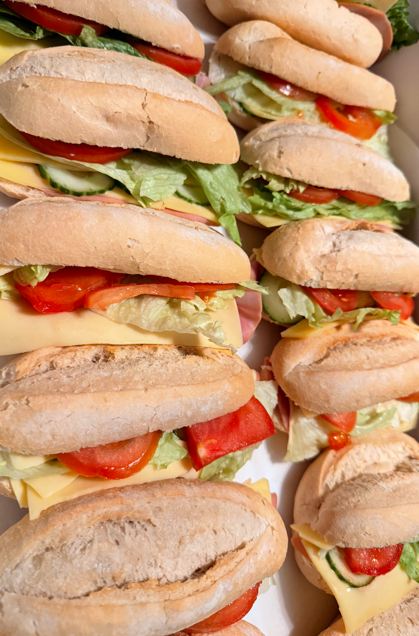 Sandwiches in een doos: broodjes gevuld met sla, tomaat, kaas en ham.