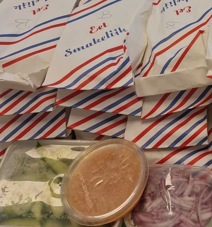 Een container met uien staat naast een stapel papieren zakken met de tekst 'eat smokesville'