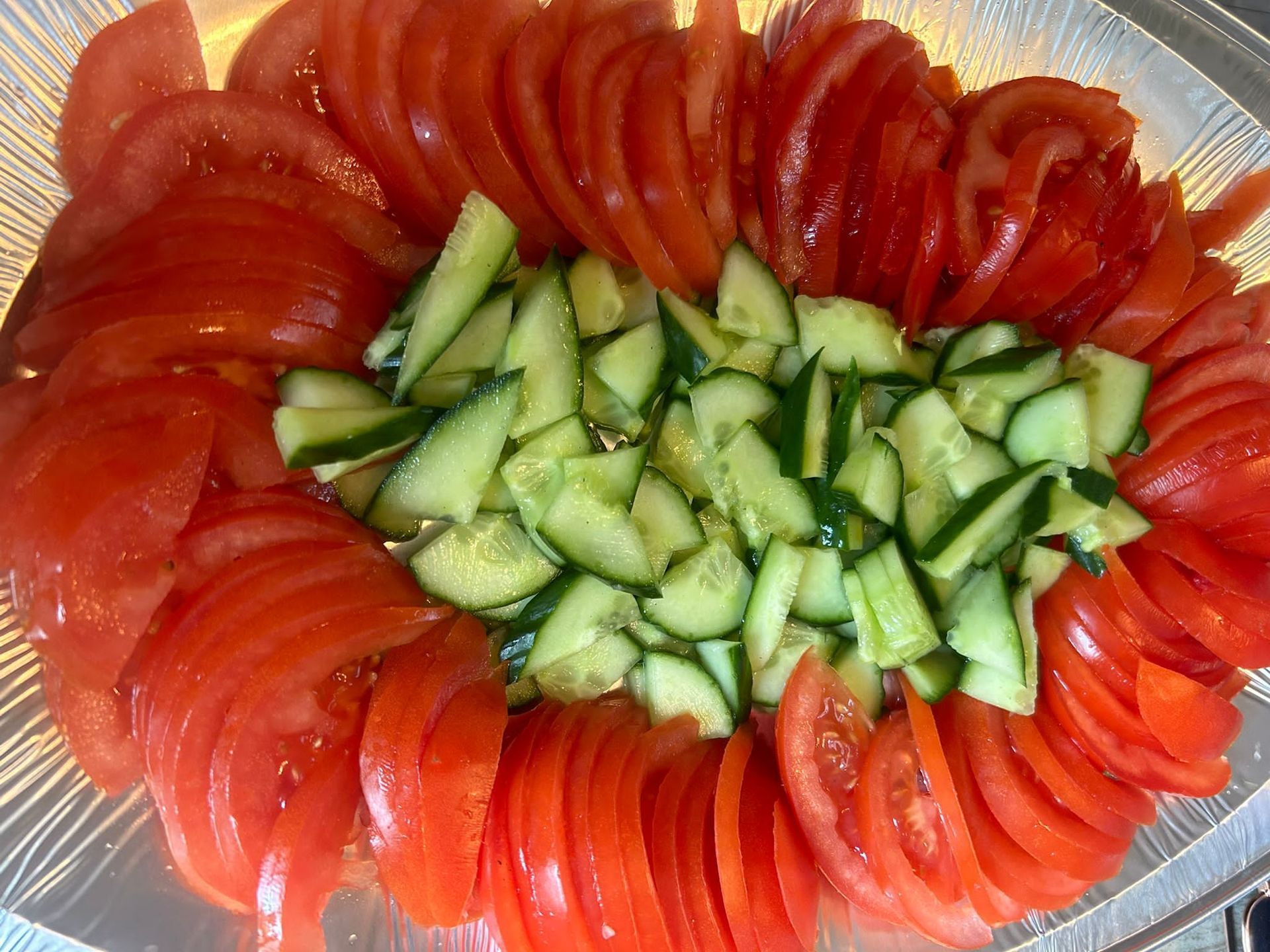Een bord met gesneden tomaten en komkommers op een tafel.
