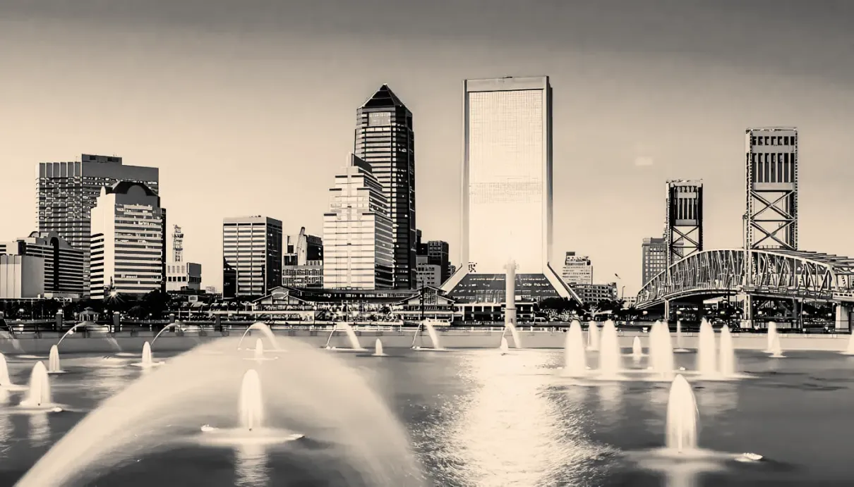 A black and white photo of a city skyline with fountains in the foreground.