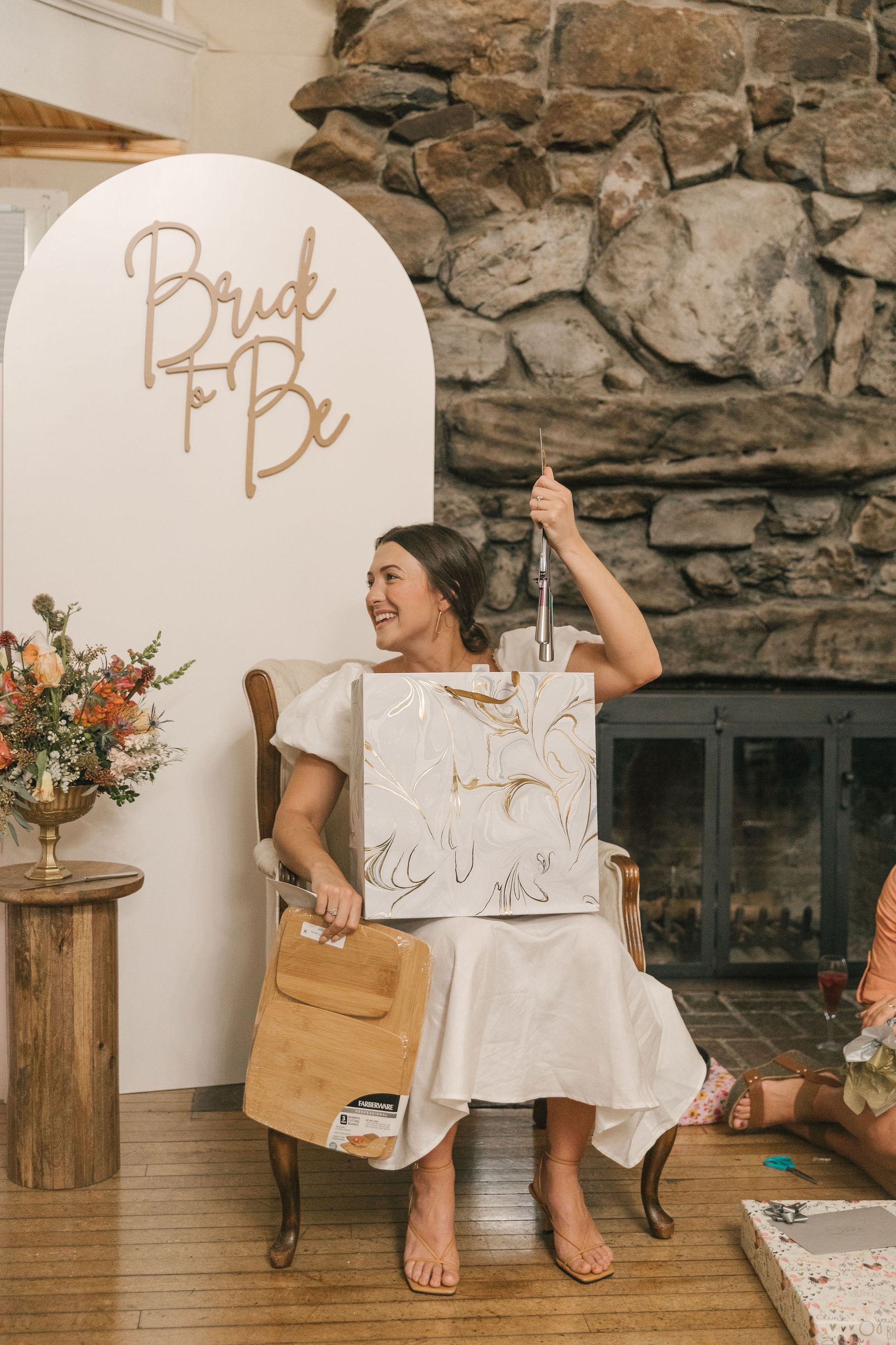 A person sits in a chair holding a gift bag in front of a 