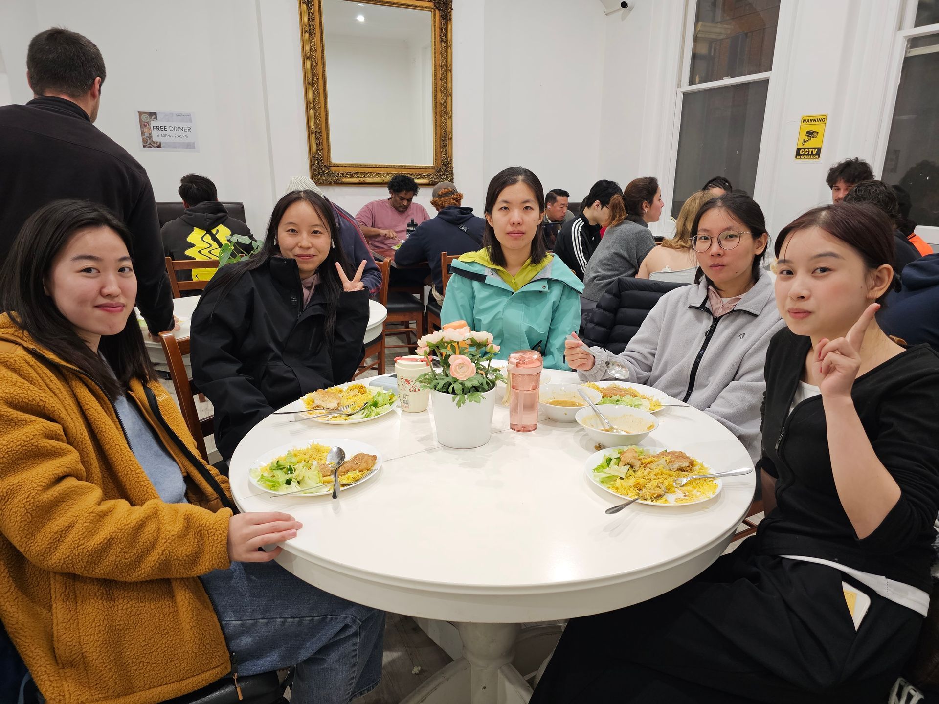 A group of East Asian women seated around a white table, smiling and posing for a photo in a dining area.