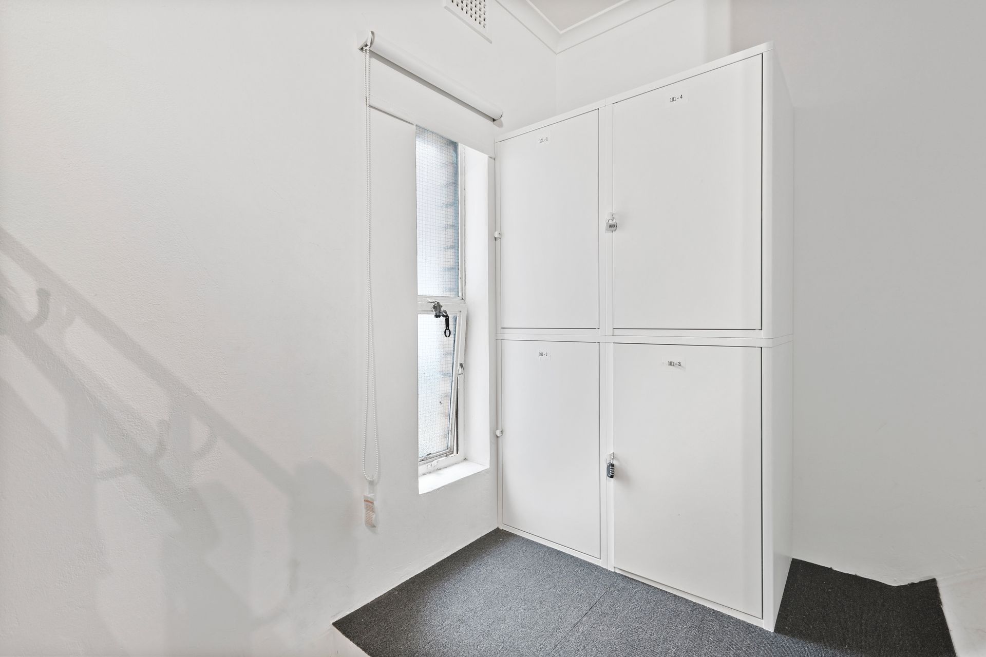 An empty room with white cabinets and a window.