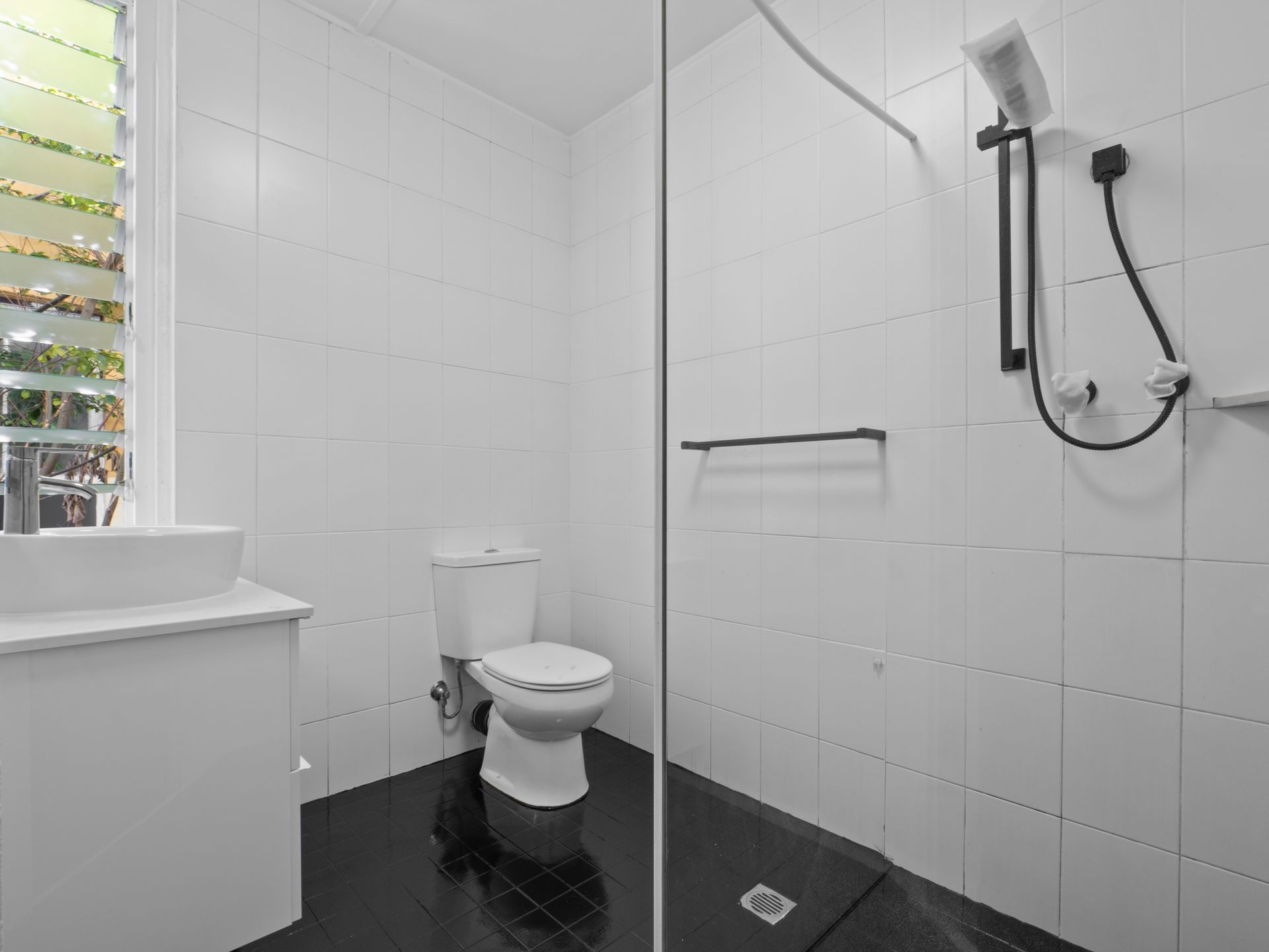A bathroom with a toilet , sink and shower.