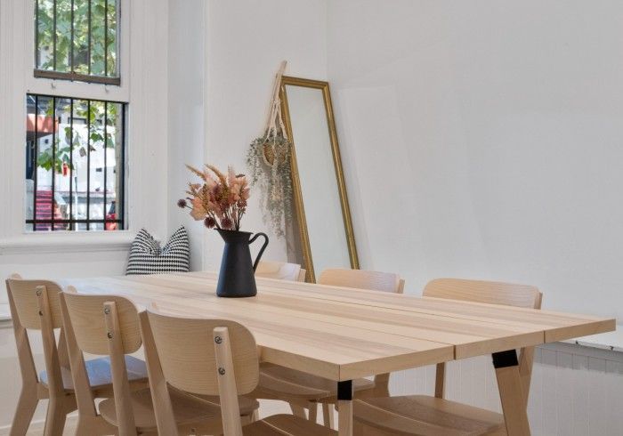 A dining room table with chairs and a vase of flowers on it.