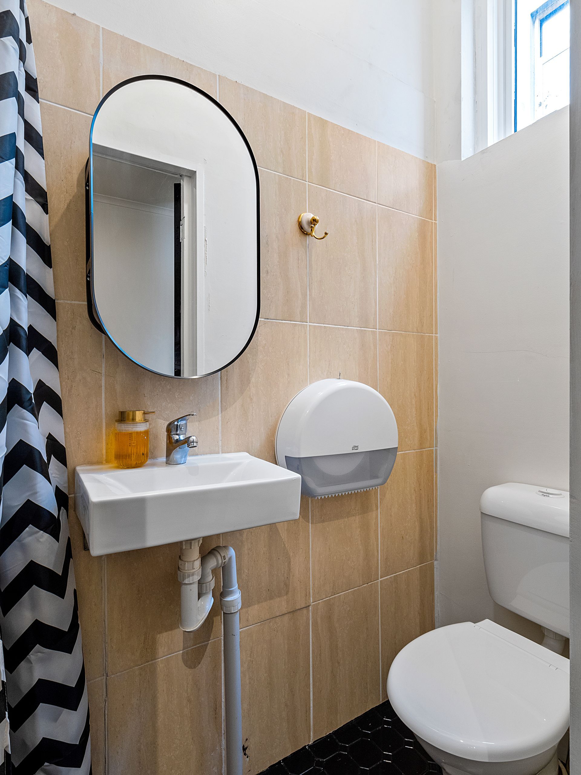 A bathroom with a toilet , sink , mirror and shower curtain.