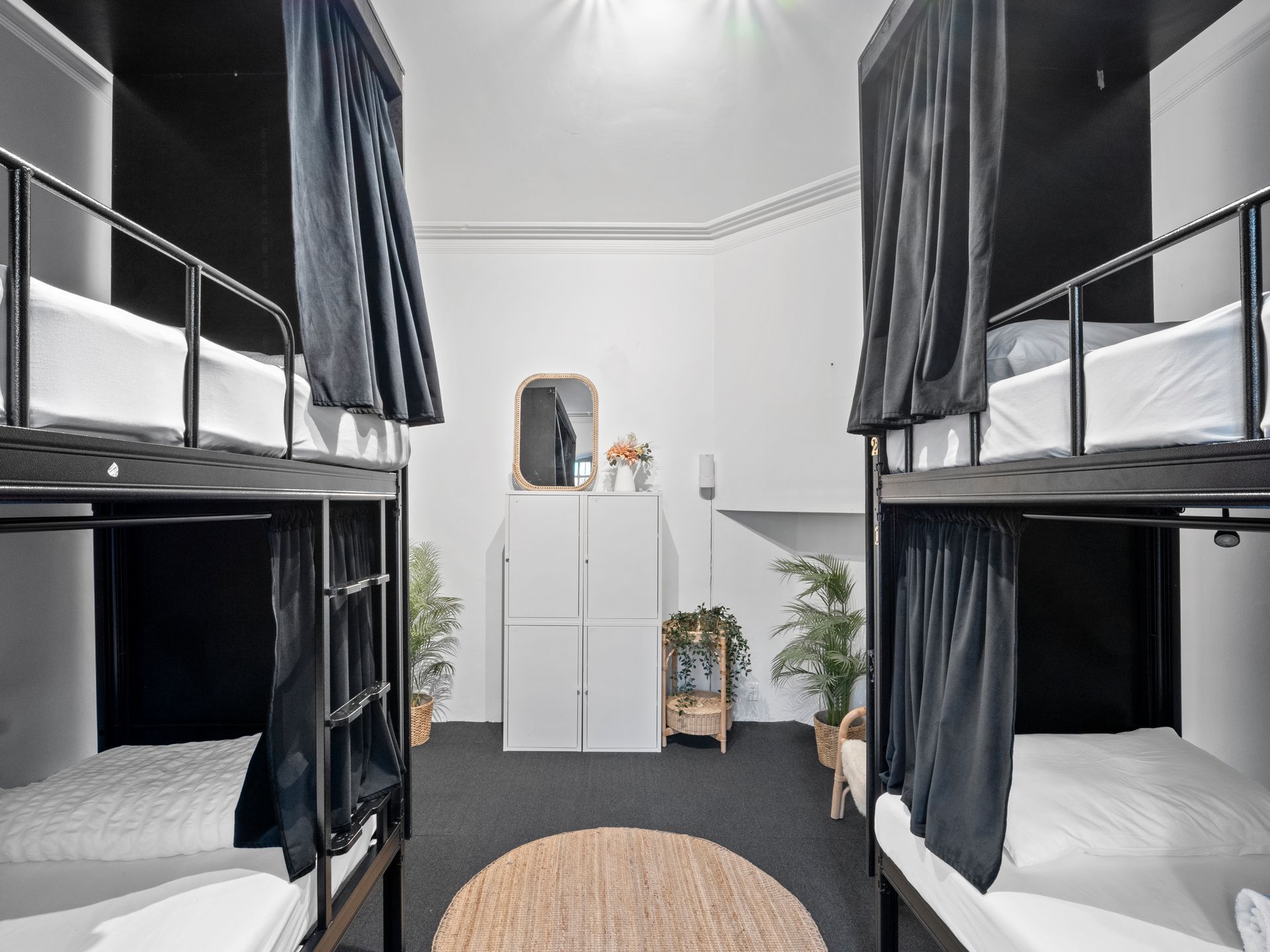 There are four bunk beds in this room with black curtains.