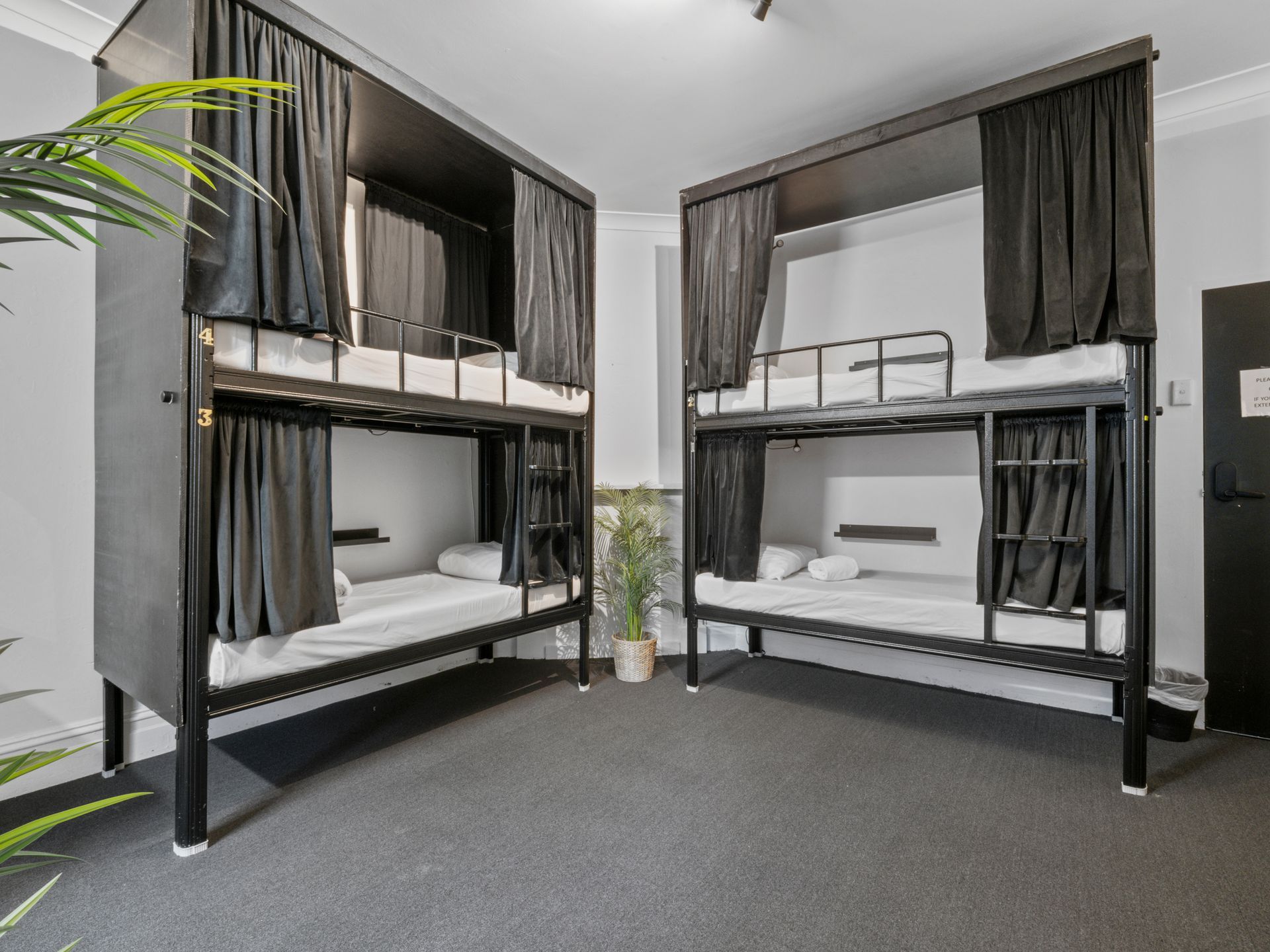 A room with four bunk beds and black curtains.