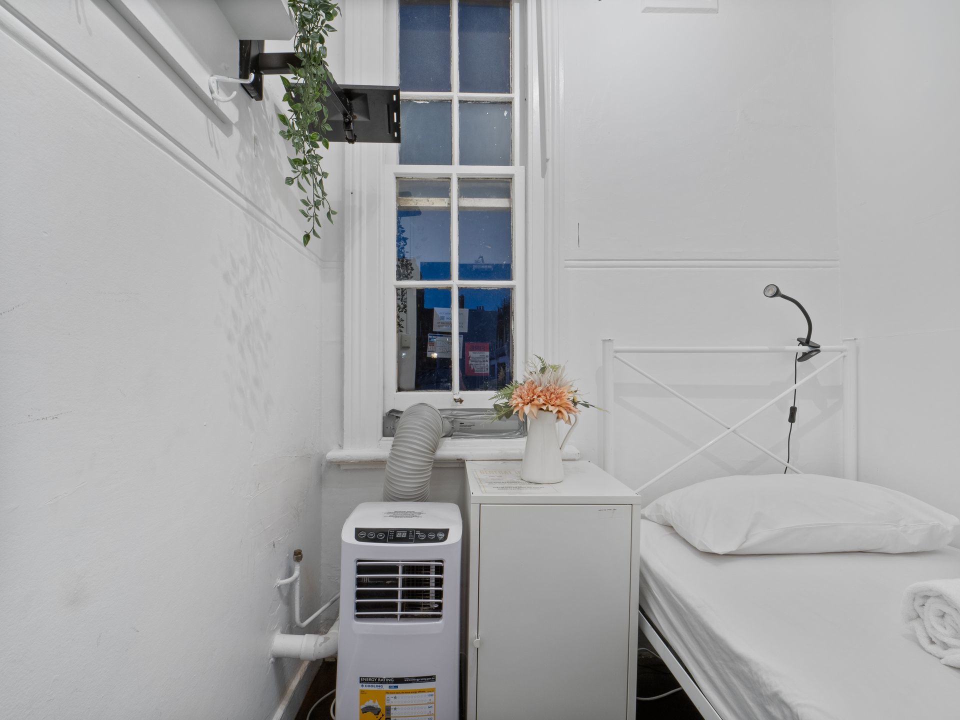 A bedroom with a single bed and a portable air conditioner.