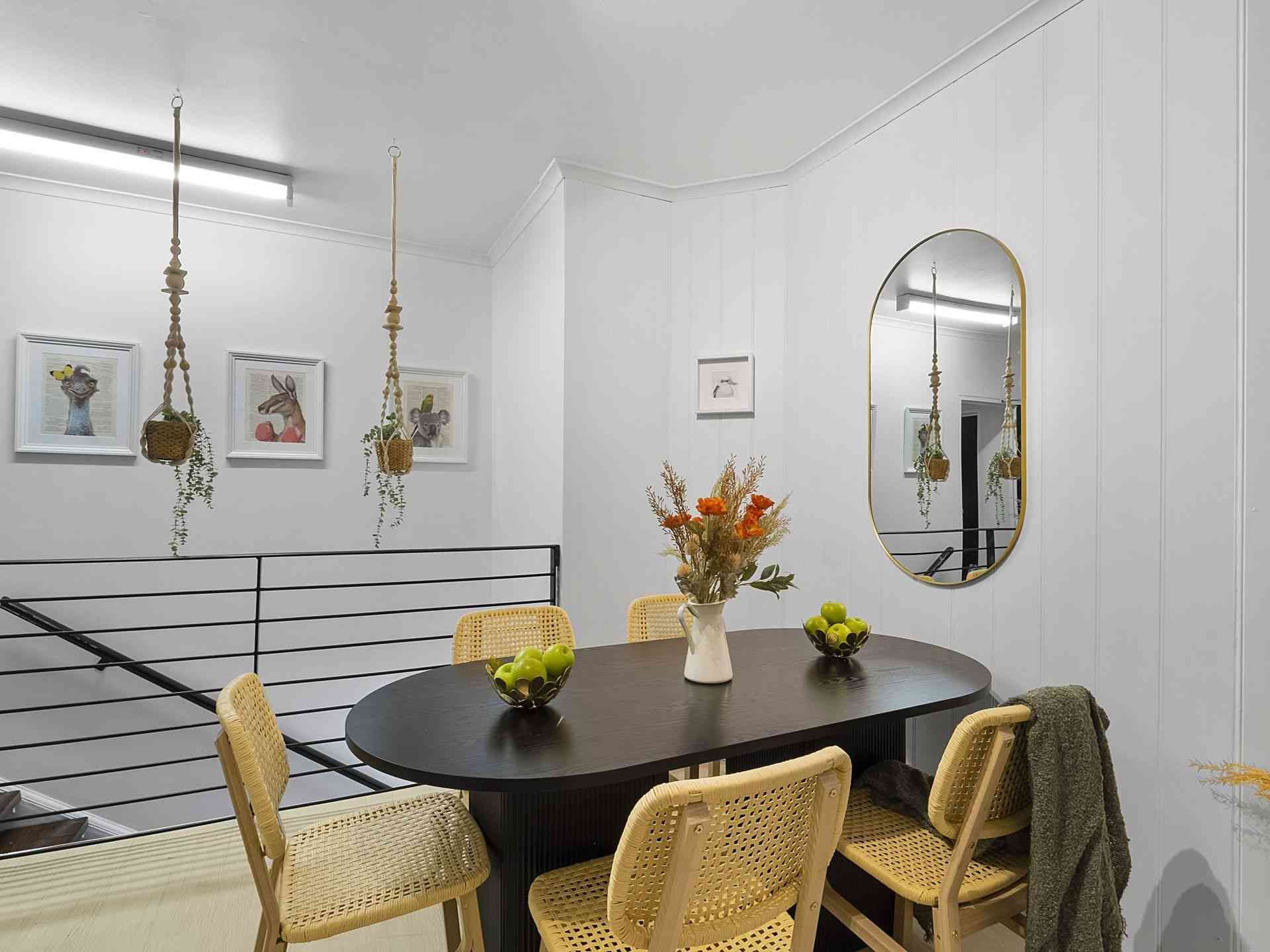 A dining room with a table and chairs and a mirror.