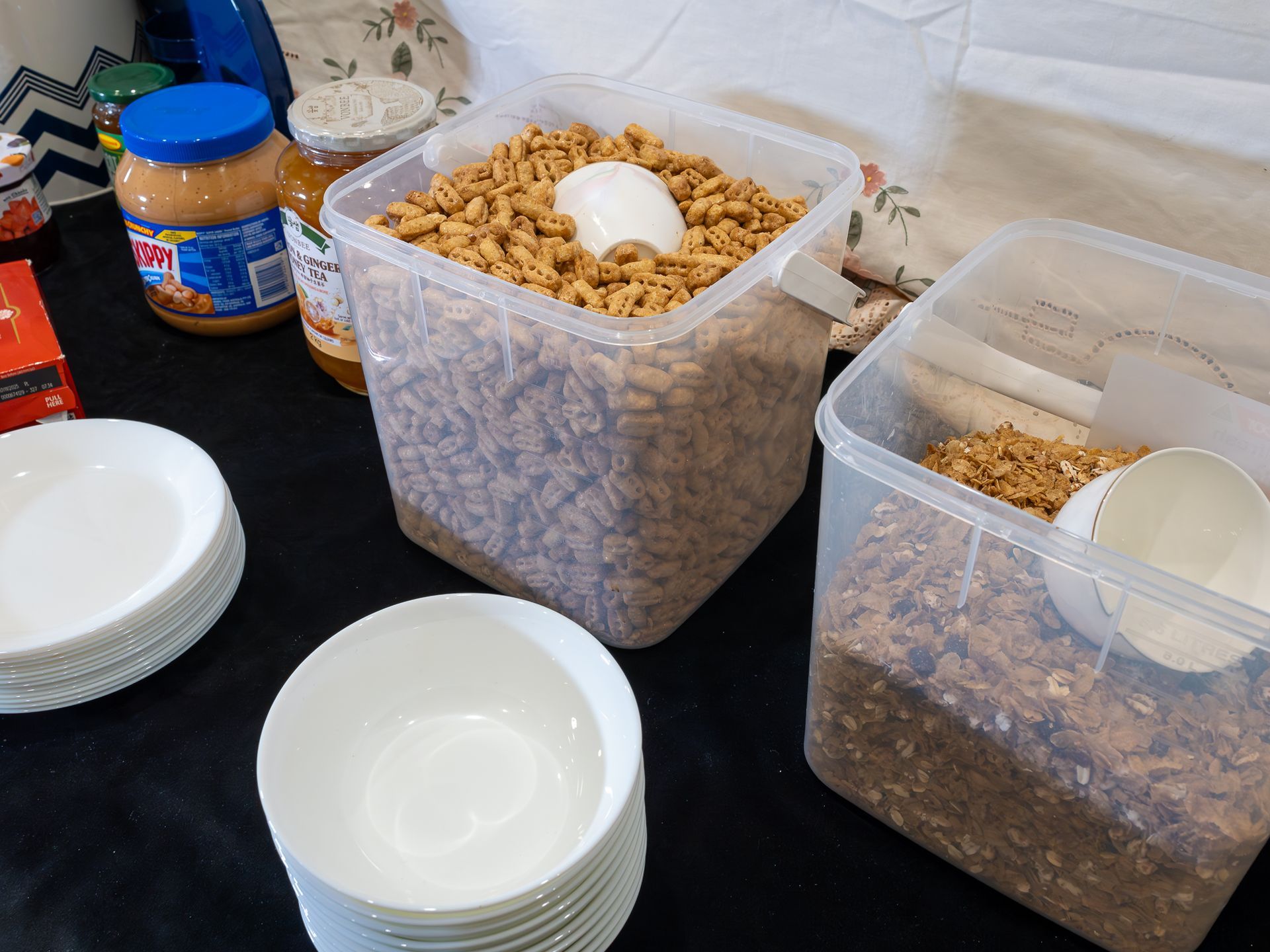 A table with containers of cereal and plates on it