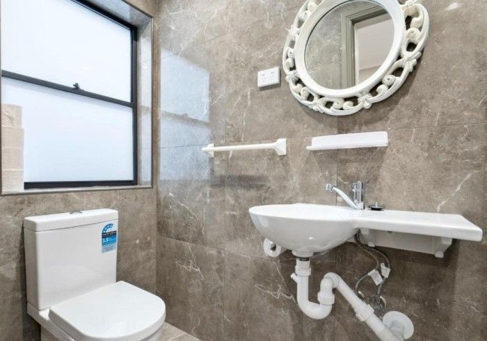 A bathroom with a toilet , sink and mirror.