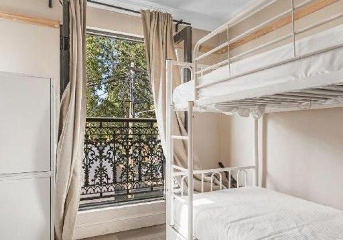 A bunk bed is sitting next to a window in a room.