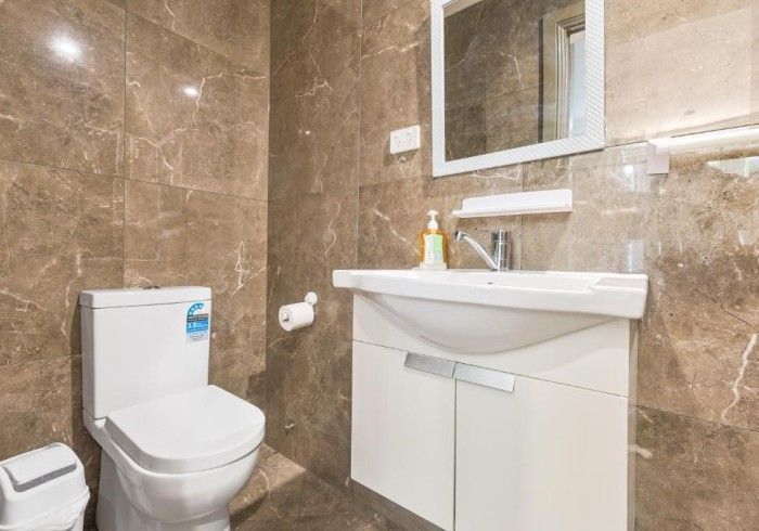 A bathroom with a toilet , sink and mirror.