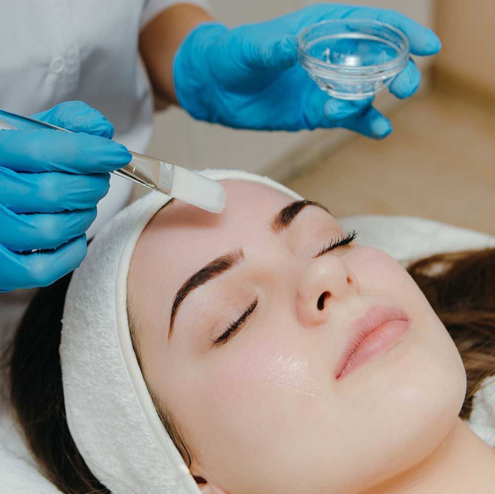 cosmetician aplying facial peeling mask