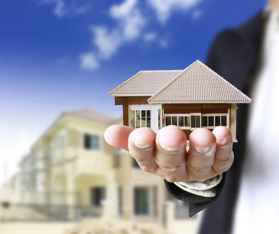 A man in a suit is holding a model house in his hand