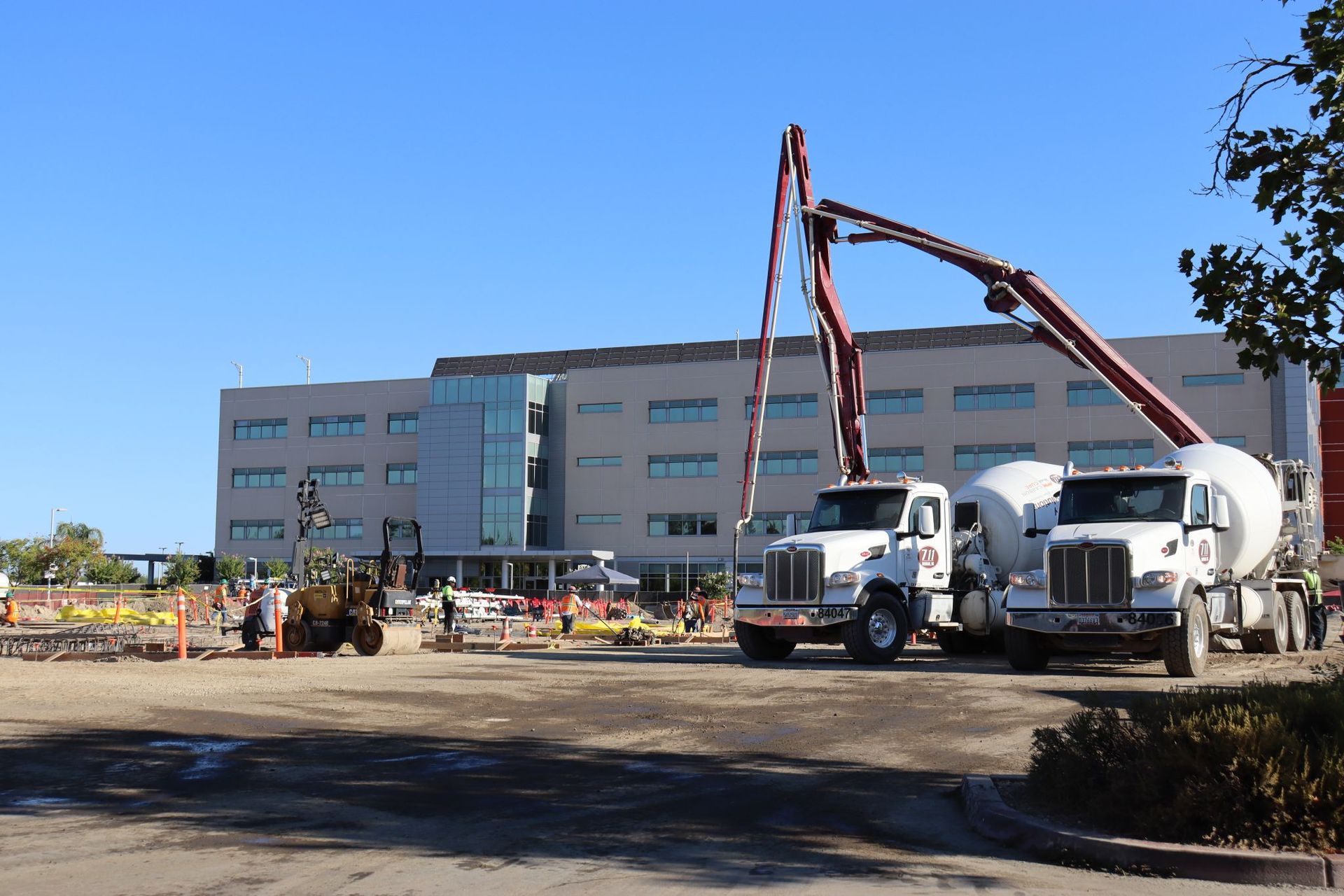 Two cement trucks are parked in front of a large building