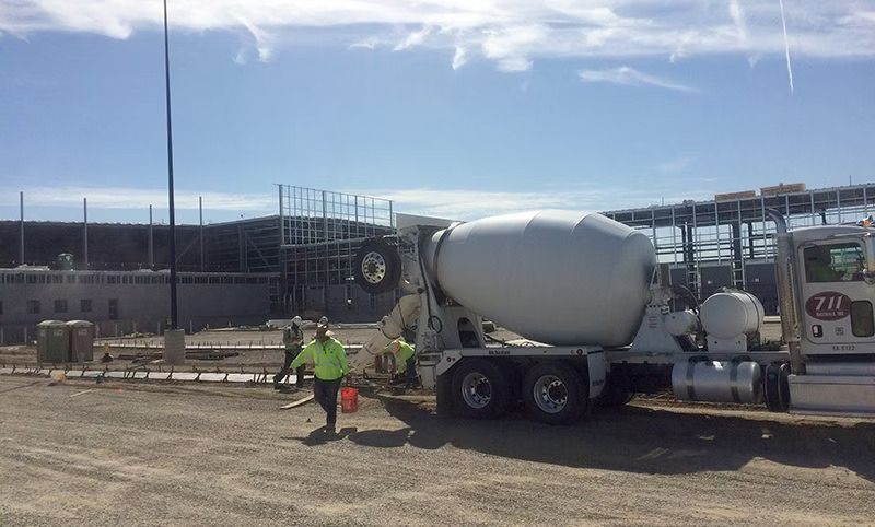 A concrete mixer truck is being loaded with concrete at a construction site.