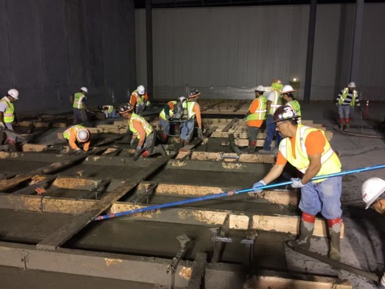 A group of construction workers are working on a concrete floor.