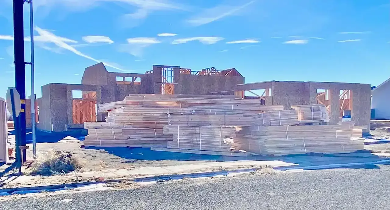 A large pile of wood is sitting in front of a house under construction in Cedar City utah