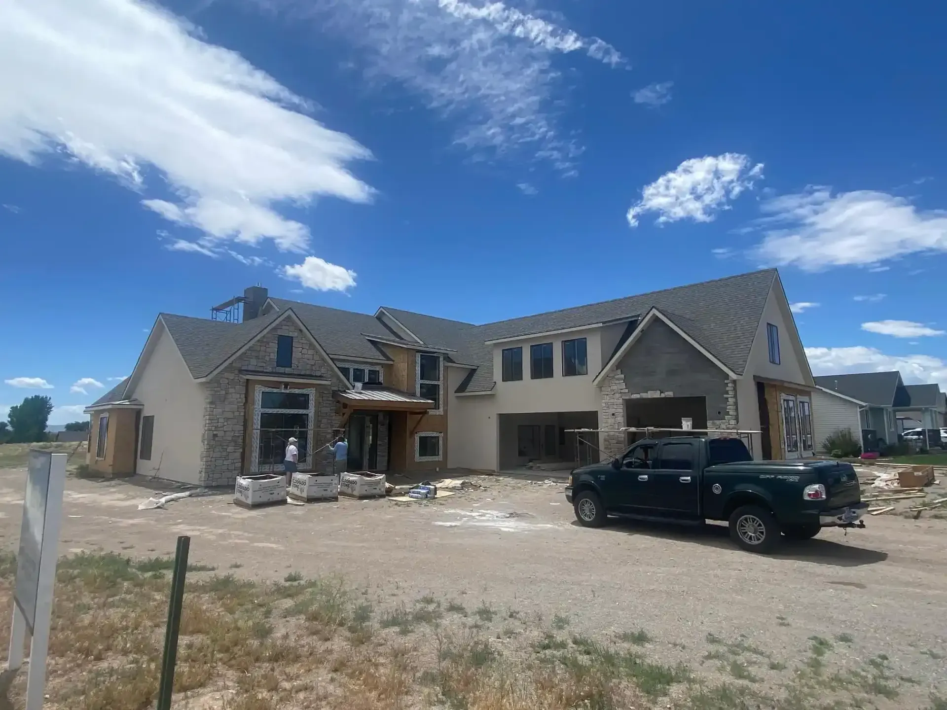 A black truck is parked in front of a large house under construction in Cedar City UT